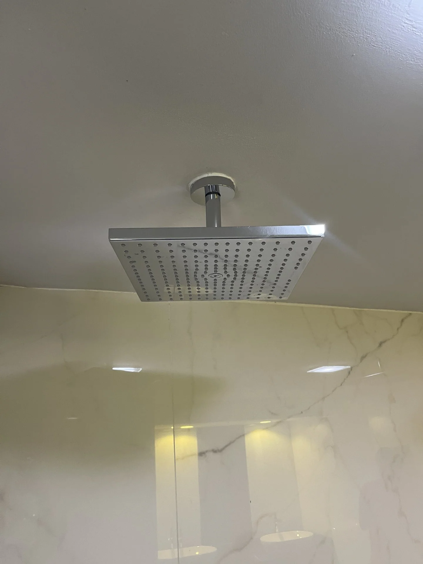 Ceiling-mounted rain shower installed over a tiled shower area
