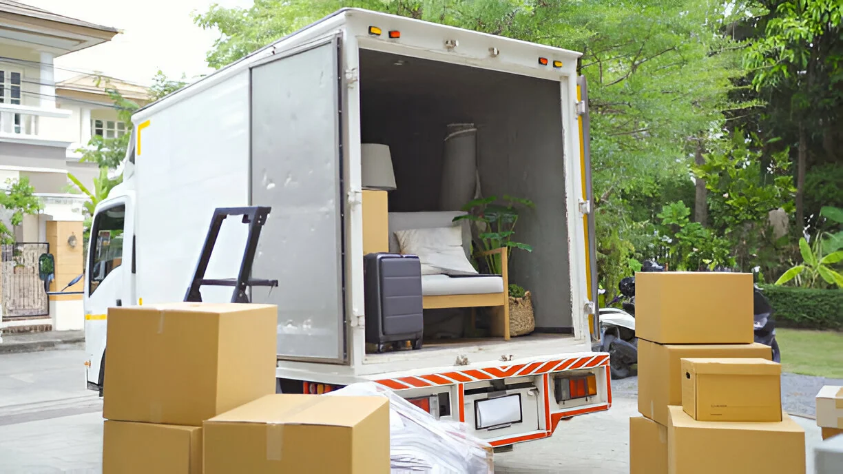 A delivery van unloading cartons and furniture outside a home