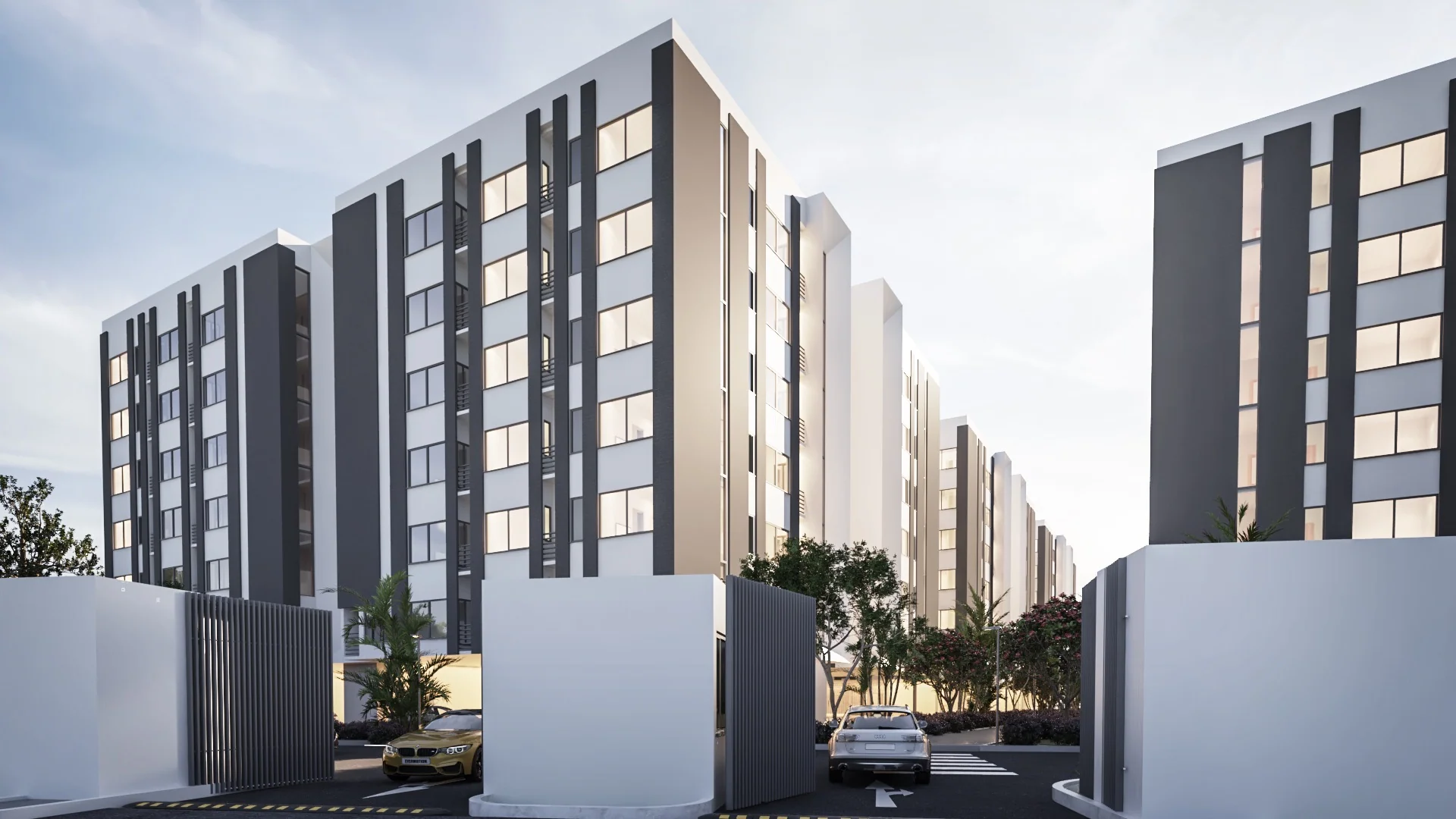 A terrace of white and charcoal apartment buildings seen down a quiet residential street at dusk