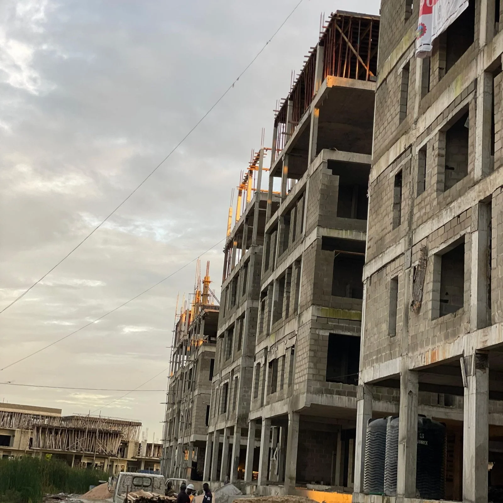 A tall Toll Heights block under construction at dusk