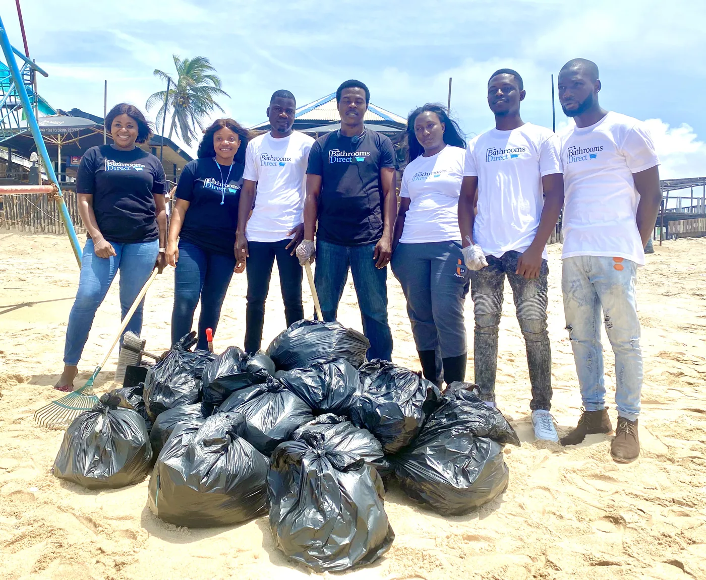 Volunteers beside bags collected during an outdoor cleanup.